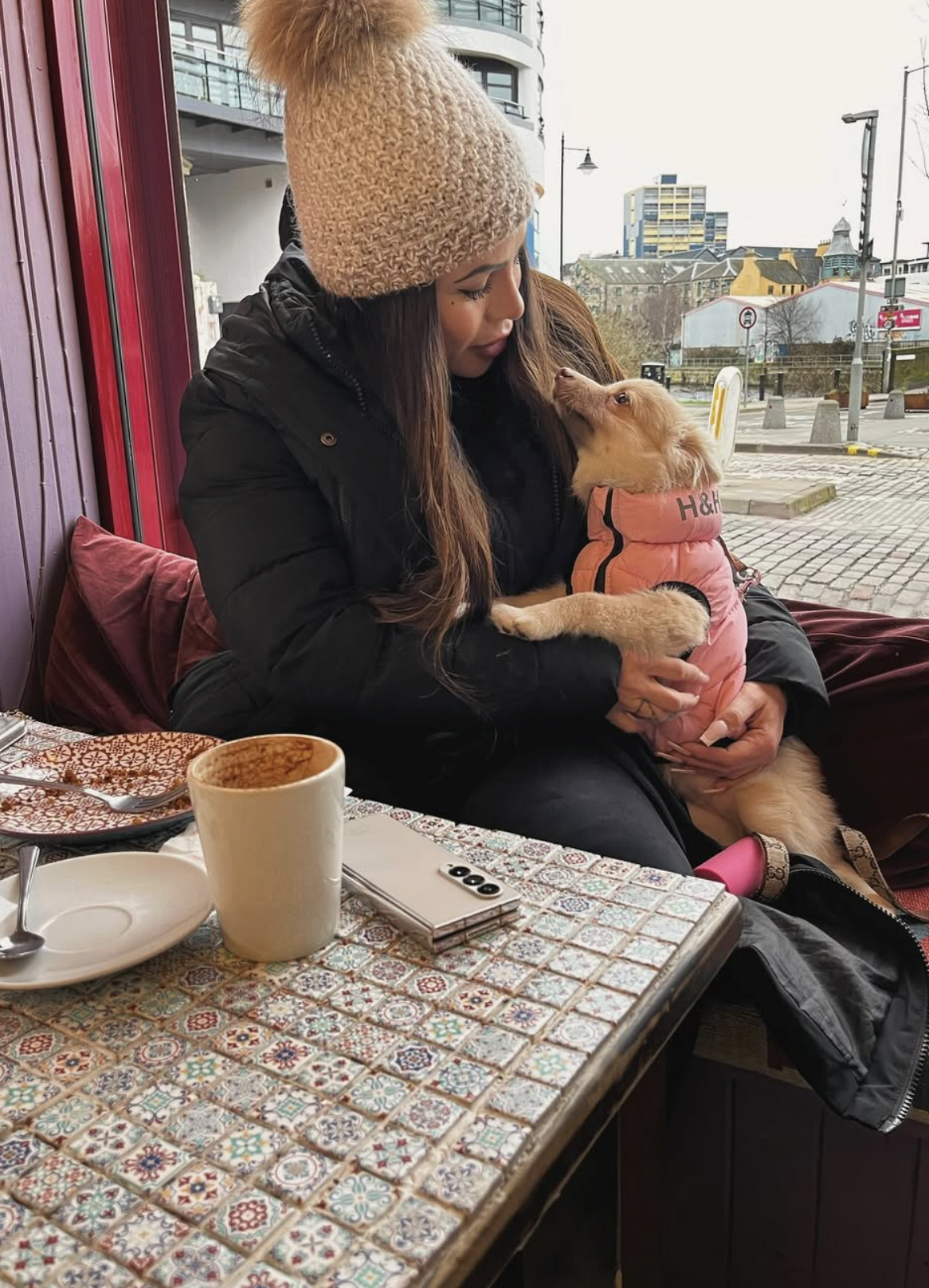 Customer with a puppy and coffee at a café table