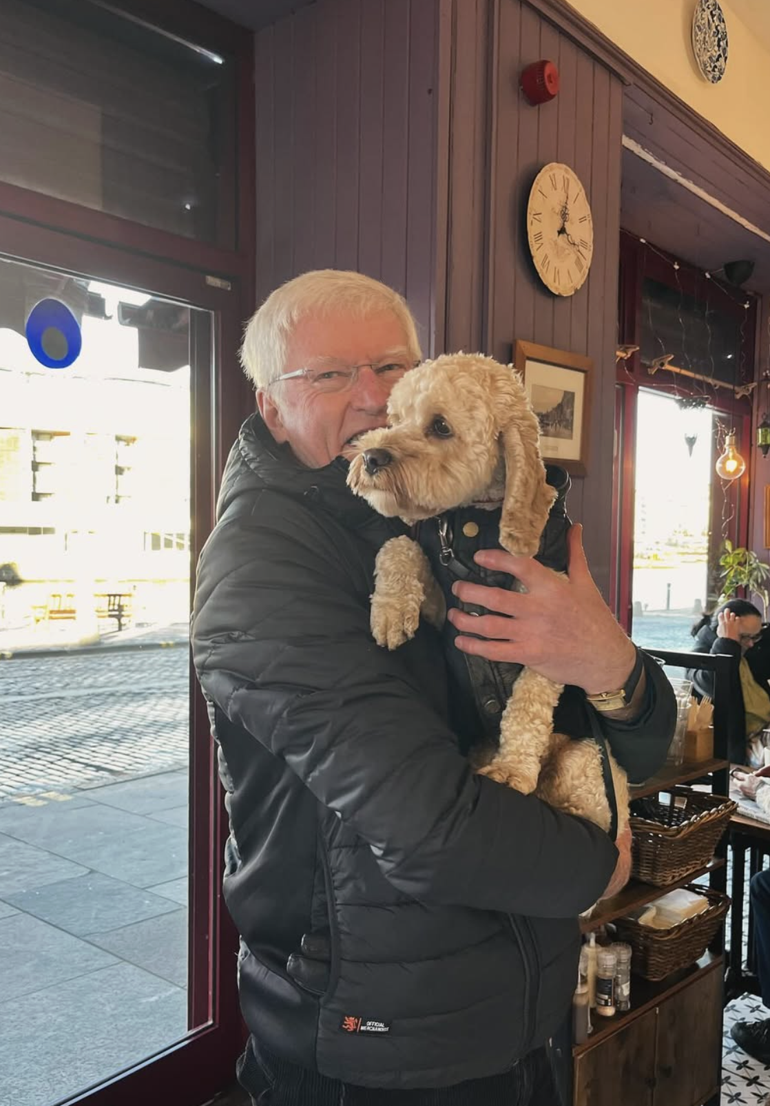 Owner holding a cockapoo dog inside the café