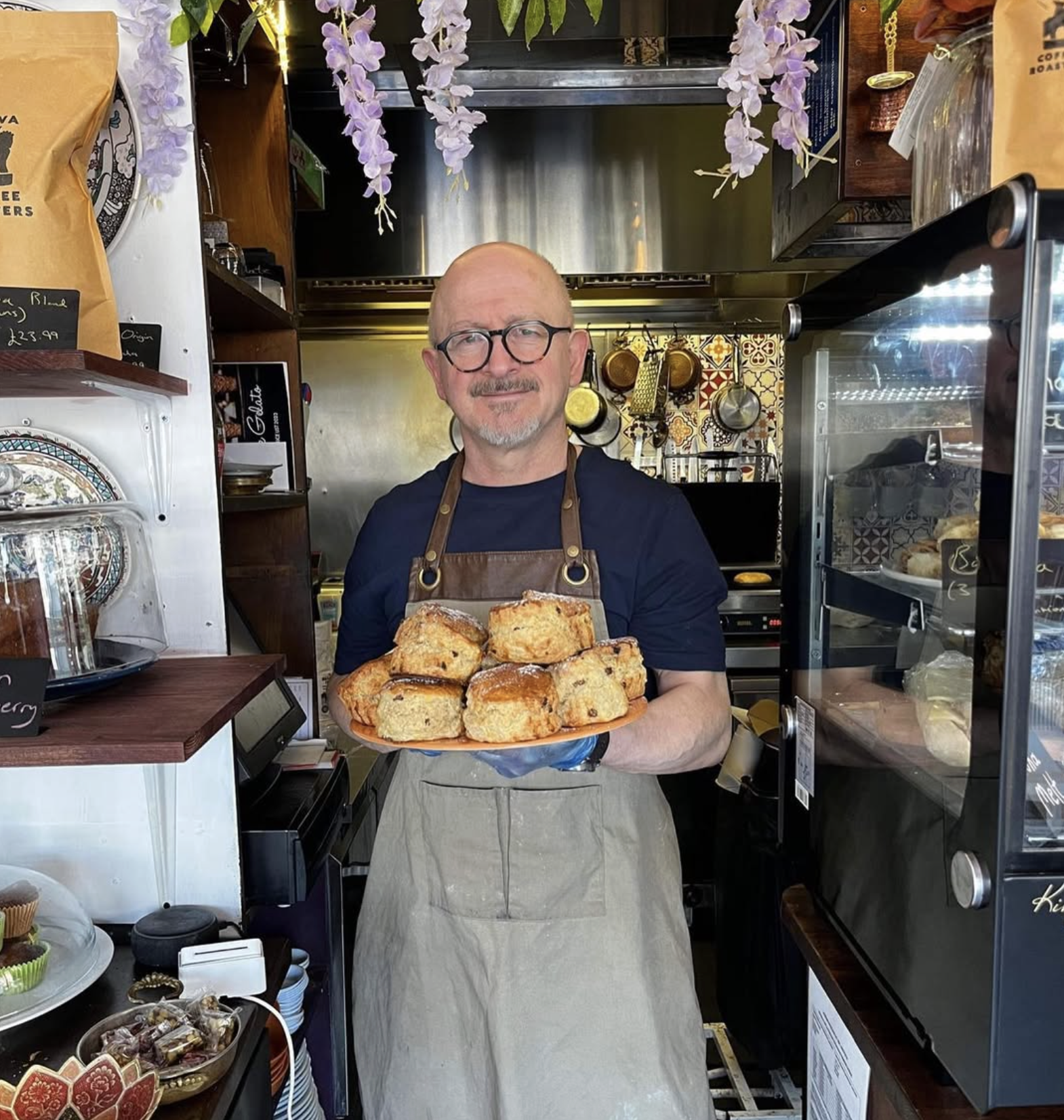 Owner holding a tray of fresh scones in the kitchen